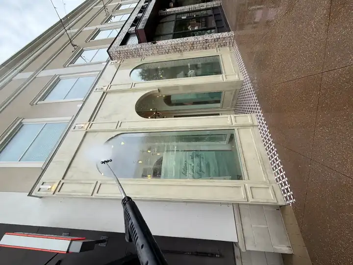 Pressure washing wand cleaning commercial stucco building facade and arched windows in Alpharetta, GA