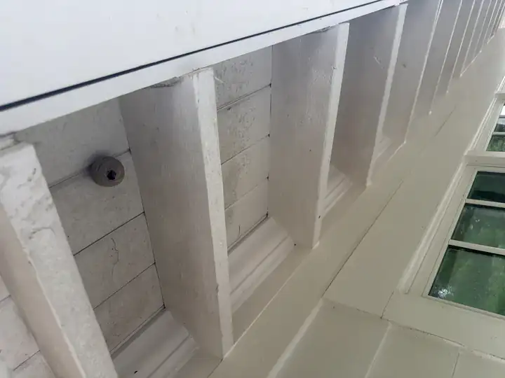 White porch soffit with a visible wasp nest and heavy mildew buildup before cleaning in Marietta, GA
