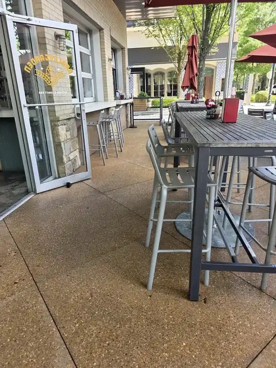 Exposed-aggregate concrete patio floor with bar-height tables and stools at a commercial degreasing job in Alpharetta, GA.