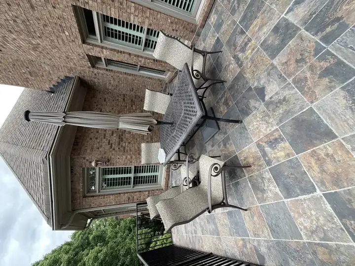 Upper tile deck with metal dining set and umbrella at a Duluth, GA residential pressure washing job.