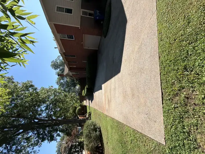 Long residential concrete driveway cleaned and brightened by pressure washing in East Point, GA