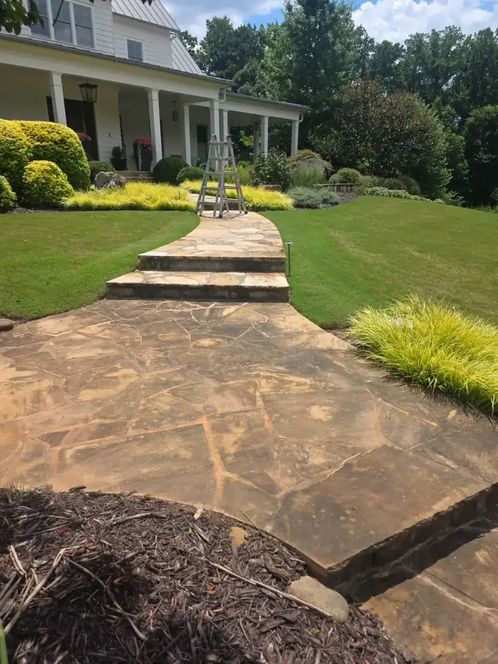 Flagstone front walkway with raised stone steps and ornamental grasses at a Milton, GA home during a pressure washing job.