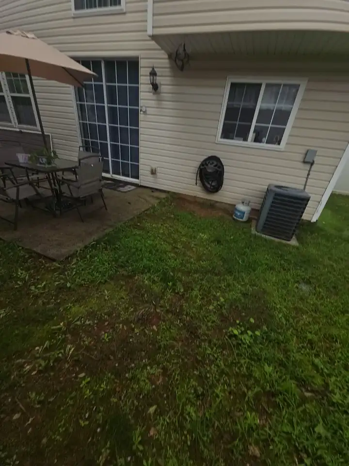 Rear of a vinyl-sided home with a small concrete patio and outdoor furniture at a house washing job in Woodstock, GA.
