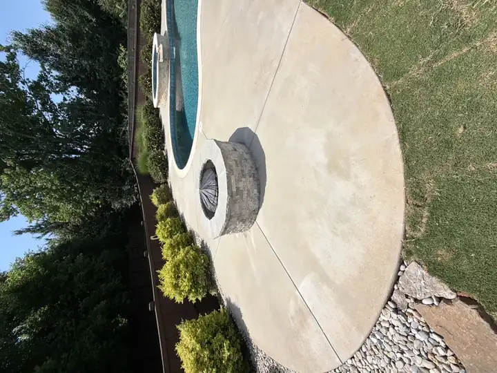 Wide view of clean concrete pool deck with stone fire pit after pressure washing service in Canton, GA