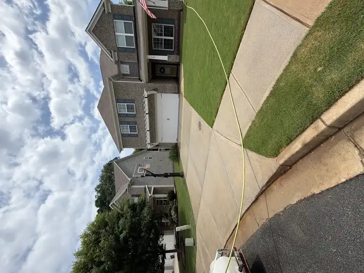 Wide-angle shot of clean concrete driveway and brick home exterior after pressure washing in Canton, GA