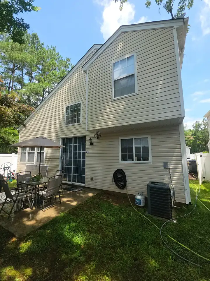 Rear of a two-story vinyl-sided home with a concrete patio and outdoor furniture at a house washing job in Woodstock, GA.