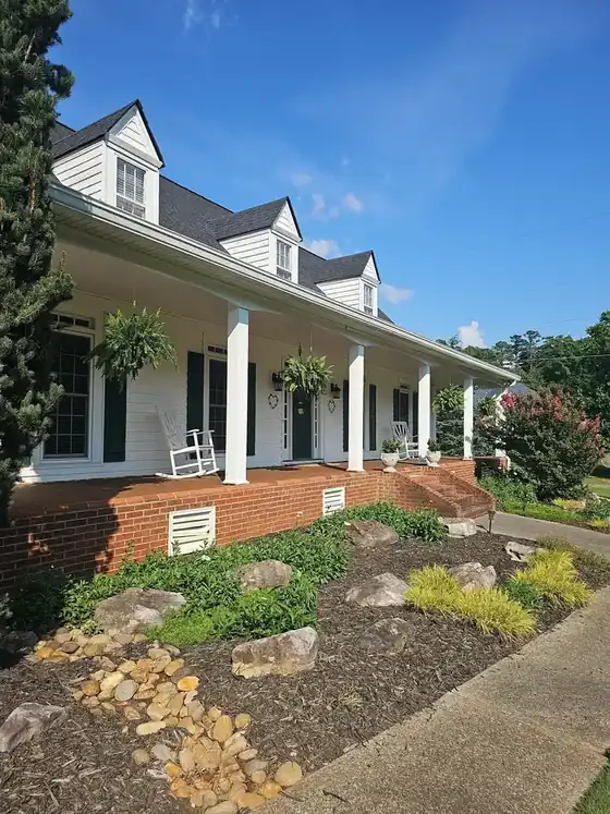 Wide shot of the front of a two-story white vinyl-sided home with a covered porch and brick foundation at a house wash in Kennesaw, GA.