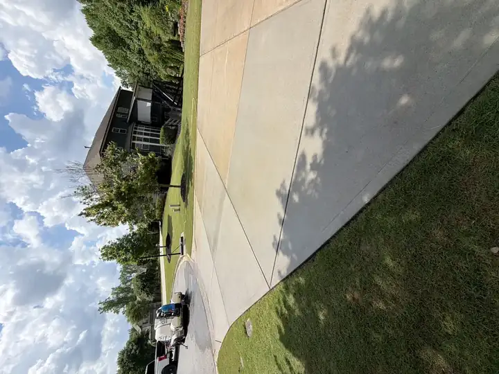 Concrete driveway pressure-washed in Canton, GA with Alpha Pressure Washing service truck and equipment trailer parked nearby, fully cleaned.