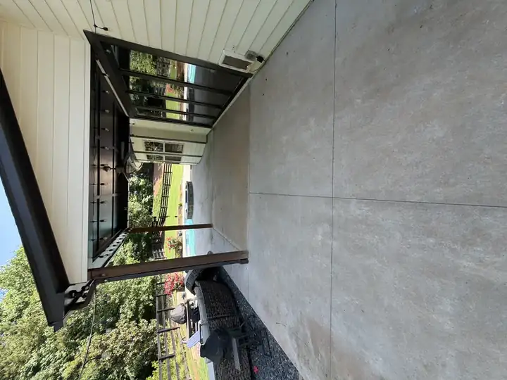 Clean concrete patio under covered pergola after pressure washing in Canton, GA, with pool and outdoor seating visible in background
