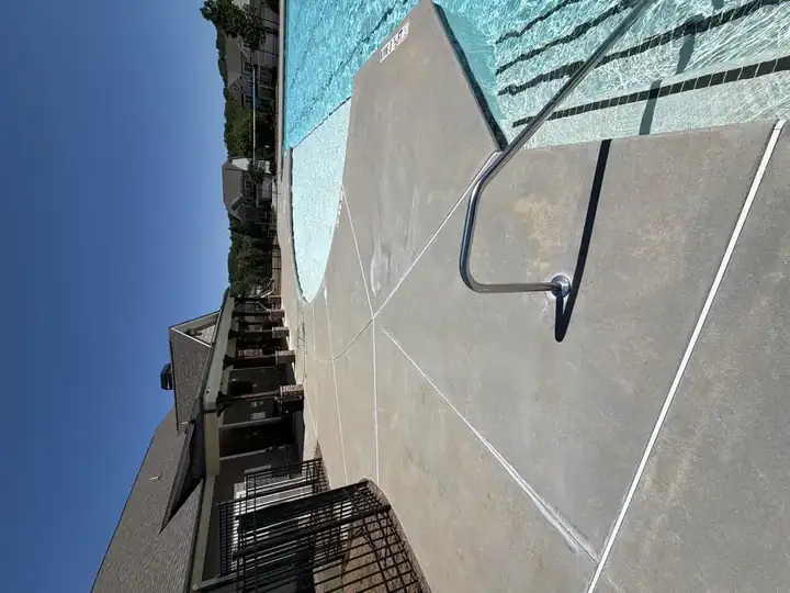 Wide-angle view of pressure-washed pool deck with pool ladder and clubhouse in background, Canton, GA