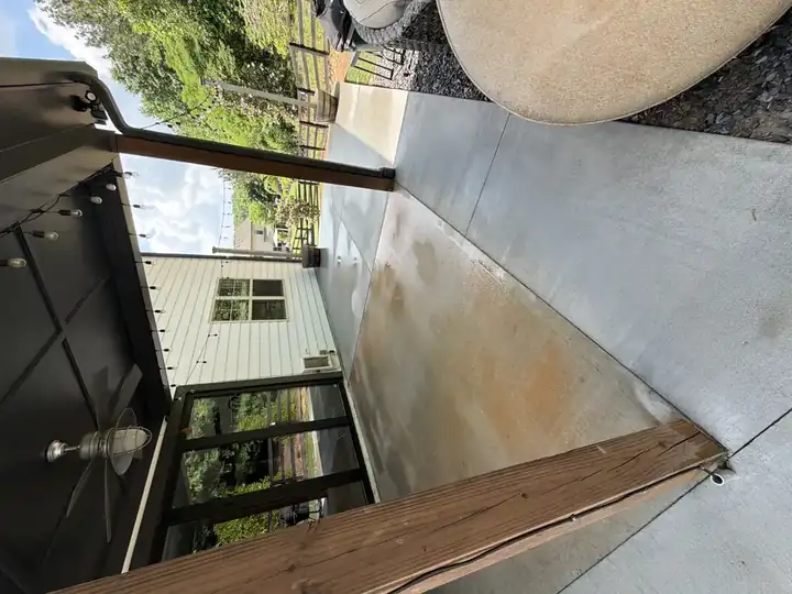 Covered concrete patio before pressure washing in Canton, GA showing rust-tinted staining and surface soiling under the pergola