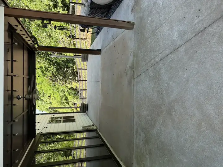 Clean covered concrete patio after pressure washing in Canton, GA, looking outward through the pergola toward the fenced backyard