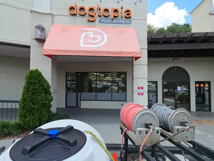 Water tank and hose reels staged on a truck in front of a commercial storefront during an awning pressure washing job in Roswell, GA.