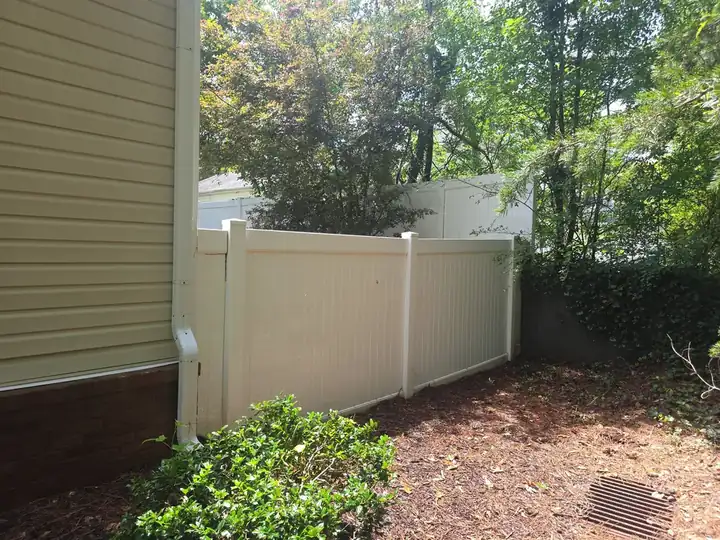 White vinyl privacy fence along the side of a residential home at a pressure washing job in Woodstock, GA.