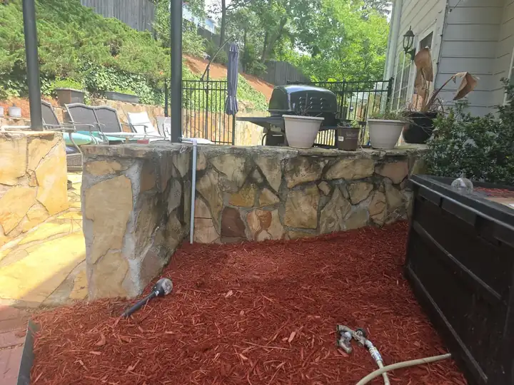 Flagstone outdoor kitchen wall and backyard area during a pool deck and house washing job in Alpharetta, GA