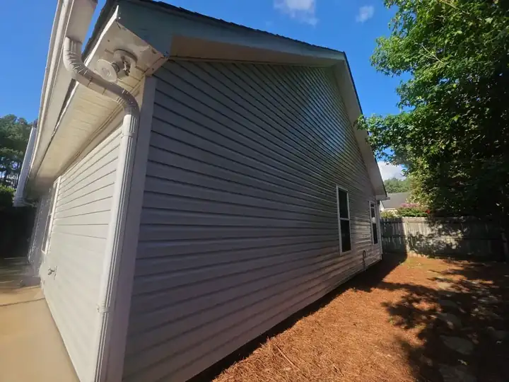 Side wall of a residential home showing gray vinyl siding and gutters at a house wash job in Woodstock, GA.