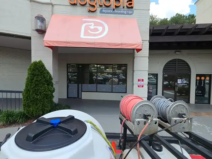 Pressure washing equipment and hose reels staged in front of a commercial storefront in Roswell, GA during an awning cleaning job.