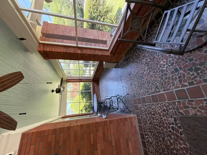 Screened porch with mosaic brick floor cleaned and chairs reset after pressure washing in East Point, GA