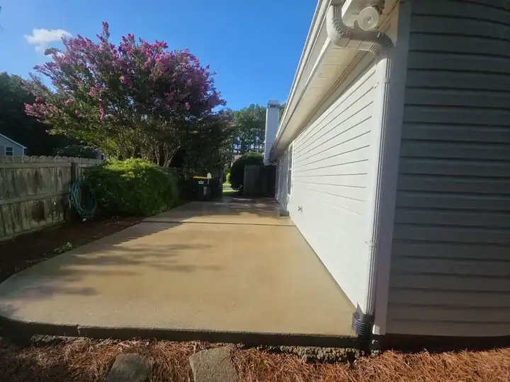 Concrete driveway along the side of a residential home in Woodstock, GA, still wet after pressure washing.