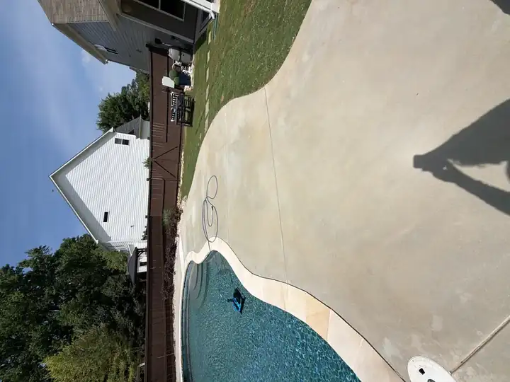 Clean concrete pool deck after pressure washing in Canton, GA, with blue pool water and backyard fence visible