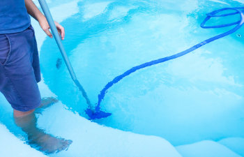 man cleaning the swimm pool on a sunny day